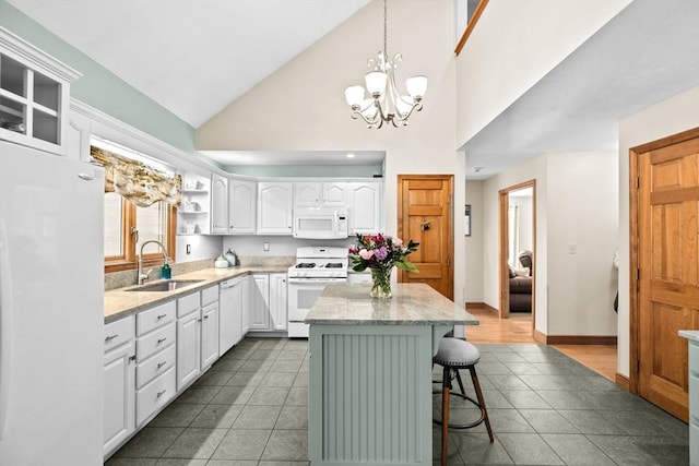 kitchen with white appliances, a kitchen island, a sink, white cabinetry, and a kitchen bar