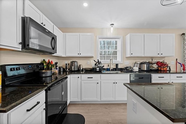 kitchen featuring black appliances, white cabinetry, light wood-style floors, and a sink