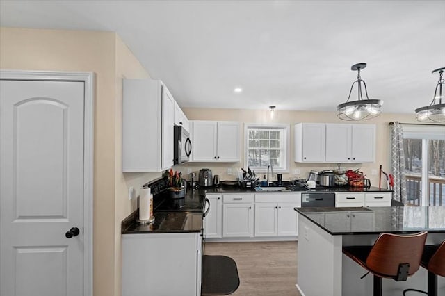 kitchen with a healthy amount of sunlight, white cabinetry, a sink, and a breakfast bar area