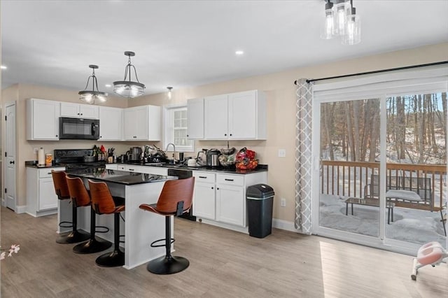 kitchen with a sink, white cabinets, a center island, black appliances, and dark countertops