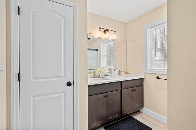 full bathroom featuring an enclosed shower, a sink, baseboards, and double vanity