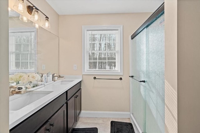 full bath featuring double vanity, tile patterned floors, a sink, and baseboards