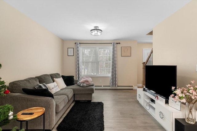 living room featuring a baseboard radiator, stairway, and wood finished floors