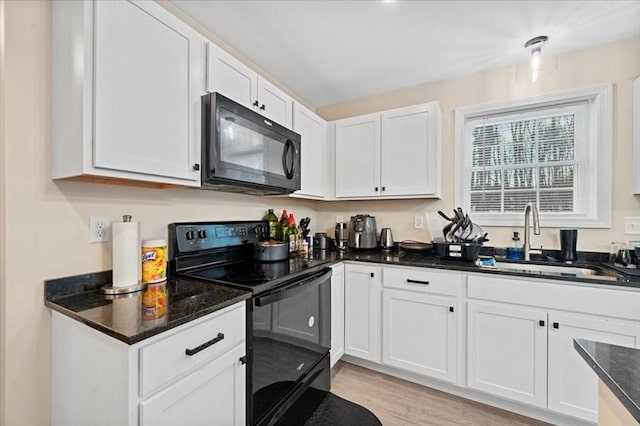 kitchen with light wood-style flooring, white cabinets, a sink, dark stone countertops, and black appliances