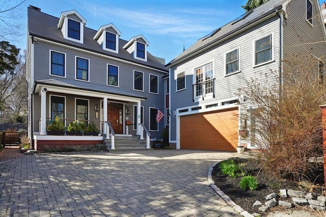 view of front of property with an attached garage, covered porch, and decorative driveway