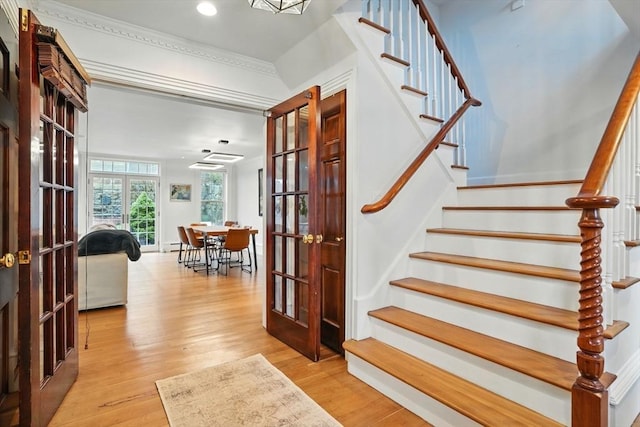 staircase with crown molding, french doors, recessed lighting, and wood finished floors