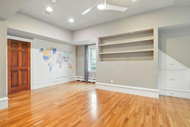 interior space with ceiling fan, visible vents, wood finished floors, a baseboard heating unit, and baseboards