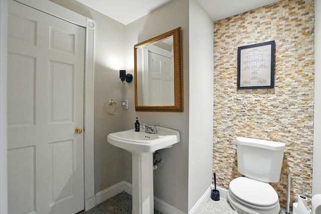 half bathroom with toilet, baseboards, and a sink