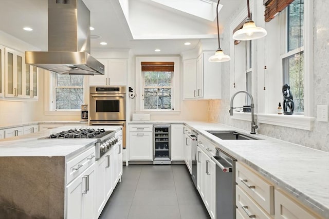 kitchen featuring plenty of natural light, a sink, appliances with stainless steel finishes, island range hood, and beverage cooler