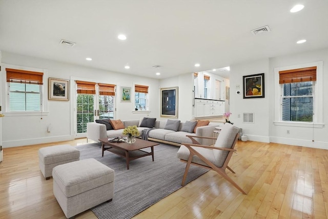 living room with visible vents, baseboards, and light wood-type flooring