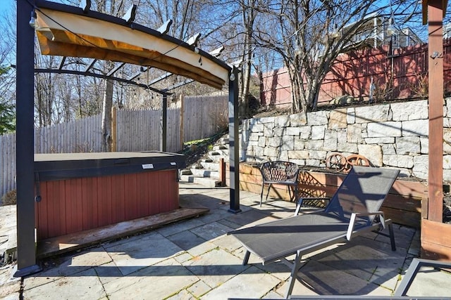 view of patio featuring fence and a hot tub