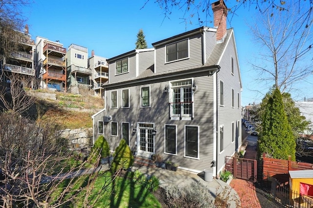 back of house with fence, a patio, and a chimney
