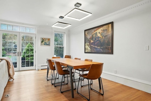 dining area featuring light wood-style flooring, a baseboard radiator, ornamental molding, and french doors
