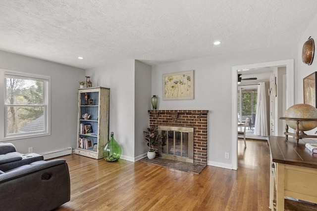 living room featuring a baseboard heating unit, a textured ceiling, and a wealth of natural light