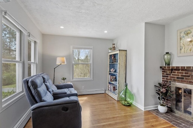living area with a textured ceiling, wood finished floors, and baseboard heating
