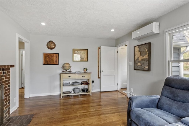 sitting room featuring a textured ceiling, a wall mounted AC, wood finished floors, and a baseboard radiator