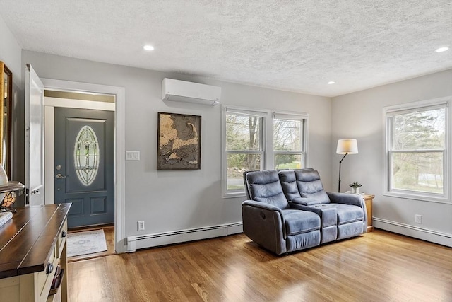 sitting room featuring an AC wall unit, a baseboard radiator, a textured ceiling, and wood finished floors