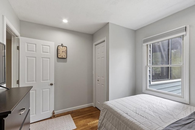bedroom with recessed lighting, baseboards, wood finished floors, and a closet