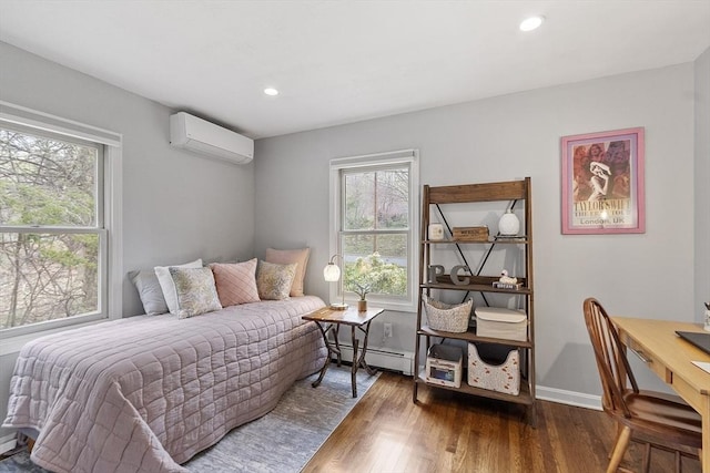 bedroom with wood finished floors, a baseboard heating unit, a wall mounted AC, and multiple windows