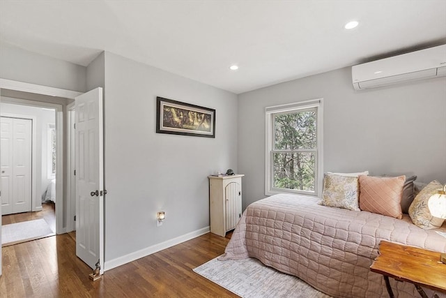 bedroom with recessed lighting, baseboards, wood finished floors, and a wall mounted air conditioner