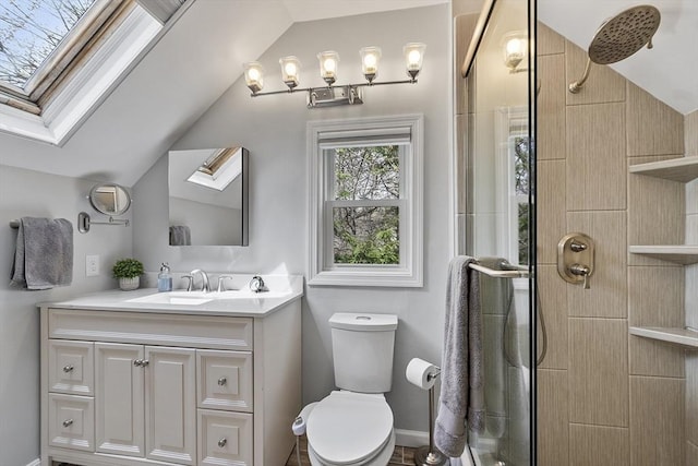 bathroom with vaulted ceiling with skylight, vanity, toilet, and tiled shower