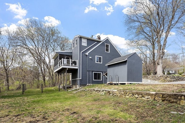 rear view of house featuring a storage unit, a chimney, a balcony, a lawn, and an outdoor structure