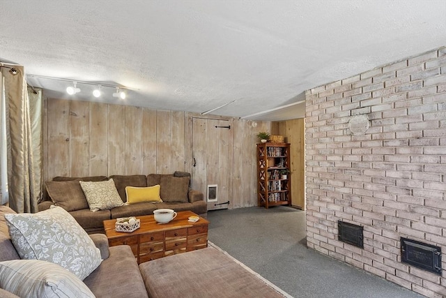 carpeted living room with wooden walls, a textured ceiling, and visible vents