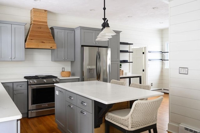 kitchen with appliances with stainless steel finishes, gray cabinetry, hanging light fixtures, a center island, and custom exhaust hood