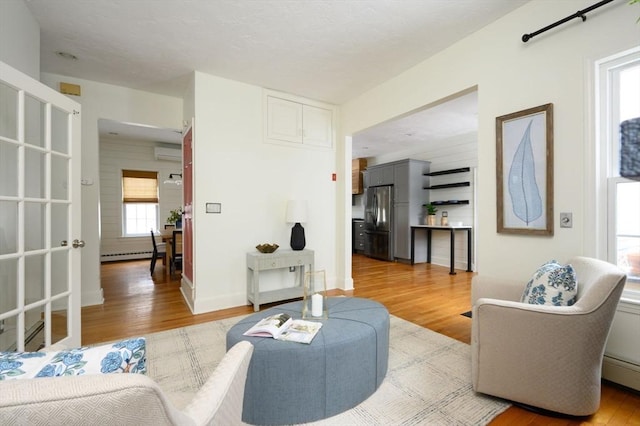 living room featuring a baseboard radiator, an AC wall unit, and light wood-type flooring