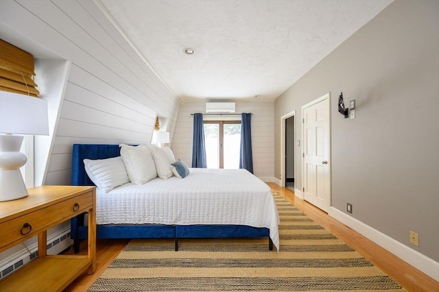 bedroom with an AC wall unit and hardwood / wood-style floors