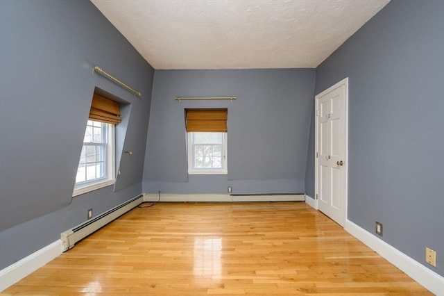 unfurnished room with light wood-type flooring and baseboard heating