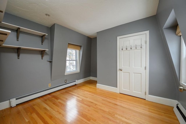 unfurnished bedroom with a baseboard radiator and light hardwood / wood-style floors