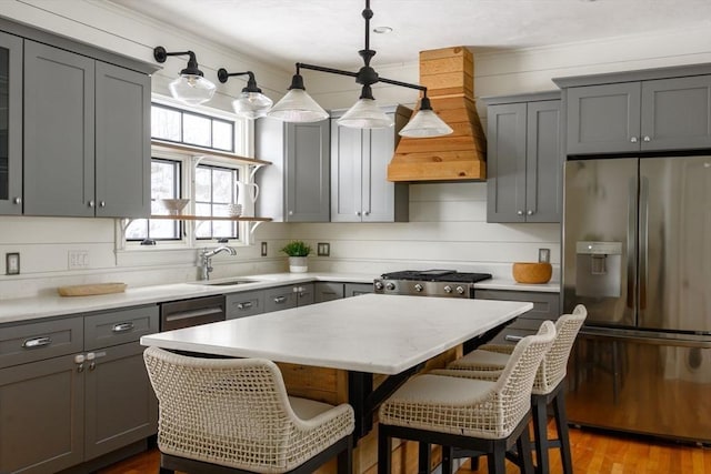 kitchen featuring a kitchen island, decorative light fixtures, sink, gray cabinetry, and stainless steel appliances