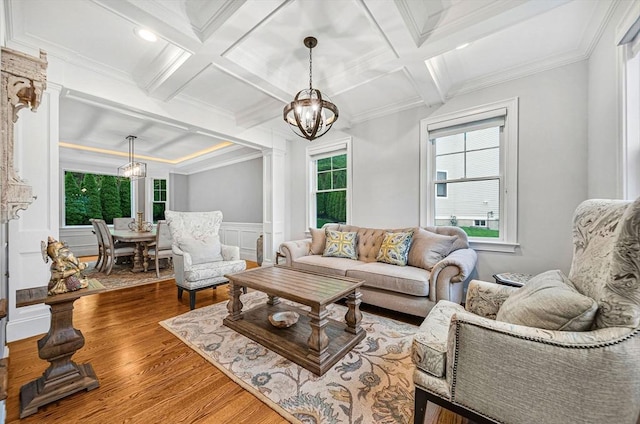 living room with an inviting chandelier, wood finished floors, coffered ceiling, beam ceiling, and crown molding