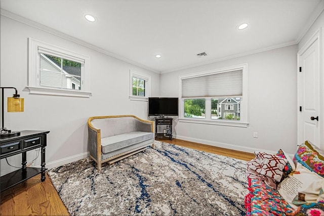 living area featuring visible vents, wood finished floors, baseboards, and ornamental molding