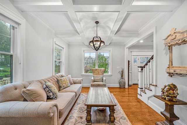 living area with light wood-style flooring, coffered ceiling, a notable chandelier, beamed ceiling, and stairs