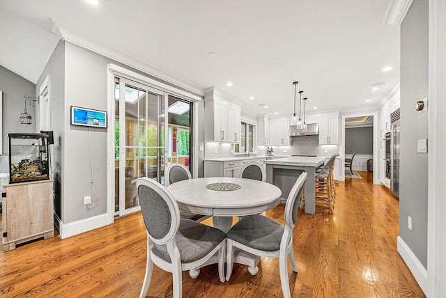 dining space featuring crown molding, baseboards, light wood finished floors, and recessed lighting