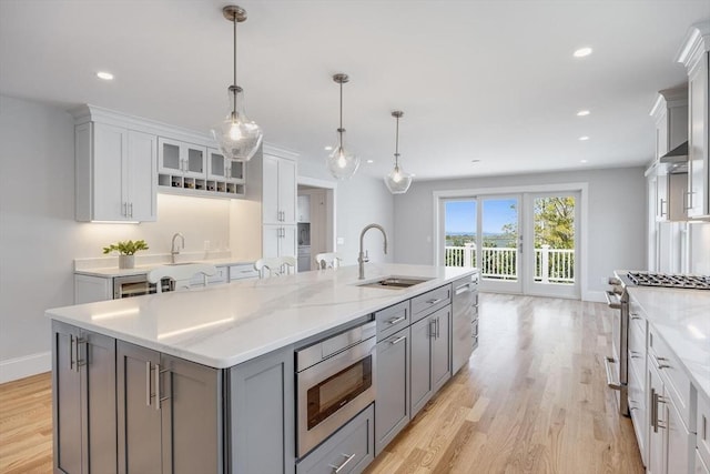 kitchen with a sink, gray cabinetry, stainless steel appliances, and light wood-style flooring