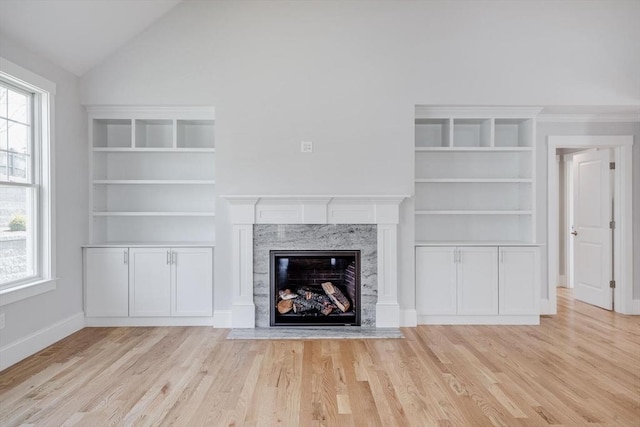 unfurnished living room featuring baseboards, vaulted ceiling, wood finished floors, and a fireplace