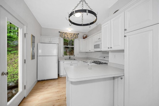 3 Chipmunk Trl Unit 3, Westford, MA 01886 - kitchen with white appliances, a sink, a peninsula, light countertops, and white cabinets