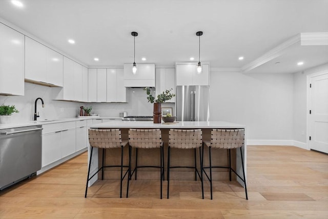 kitchen with modern cabinets, a sink, a kitchen breakfast bar, appliances with stainless steel finishes, and white cabinets