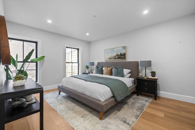 bedroom with multiple windows, wood finished floors, and baseboards