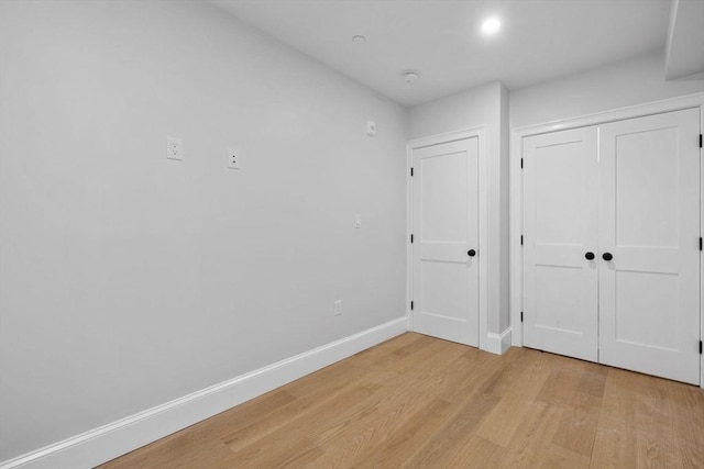 unfurnished bedroom with a closet, baseboards, and light wood finished floors