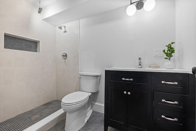 bathroom featuring vanity, toilet, baseboards, and a tile shower