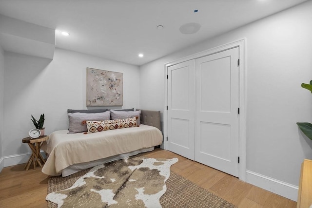 bedroom featuring a closet, recessed lighting, baseboards, and light wood finished floors