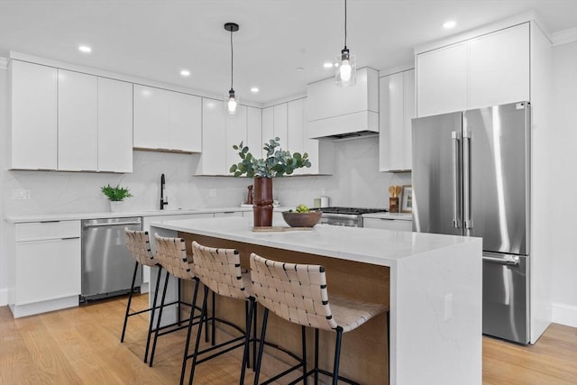 kitchen with a sink, light wood-style floors, a kitchen island, and stainless steel appliances