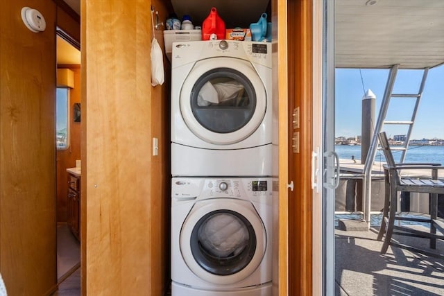 laundry room featuring laundry area, stacked washing maching and dryer, and a water view