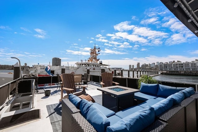 view of patio featuring a view of city, an outdoor living space with a fire pit, and a water view