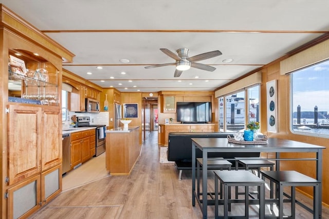 kitchen with light wood-type flooring, backsplash, a center island, stainless steel appliances, and light countertops