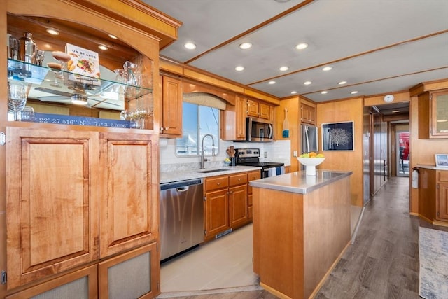 kitchen with brown cabinetry, a sink, stainless steel appliances, light countertops, and a center island